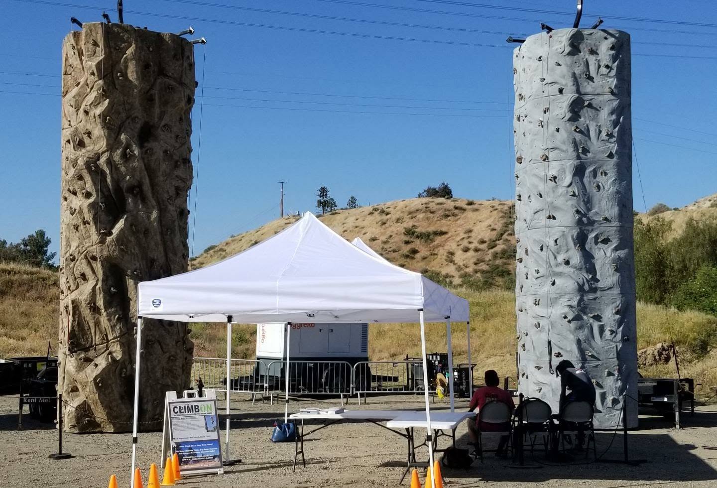 Two Climb On mobile climbing walls with a canopy and equipment area at an outdoor event